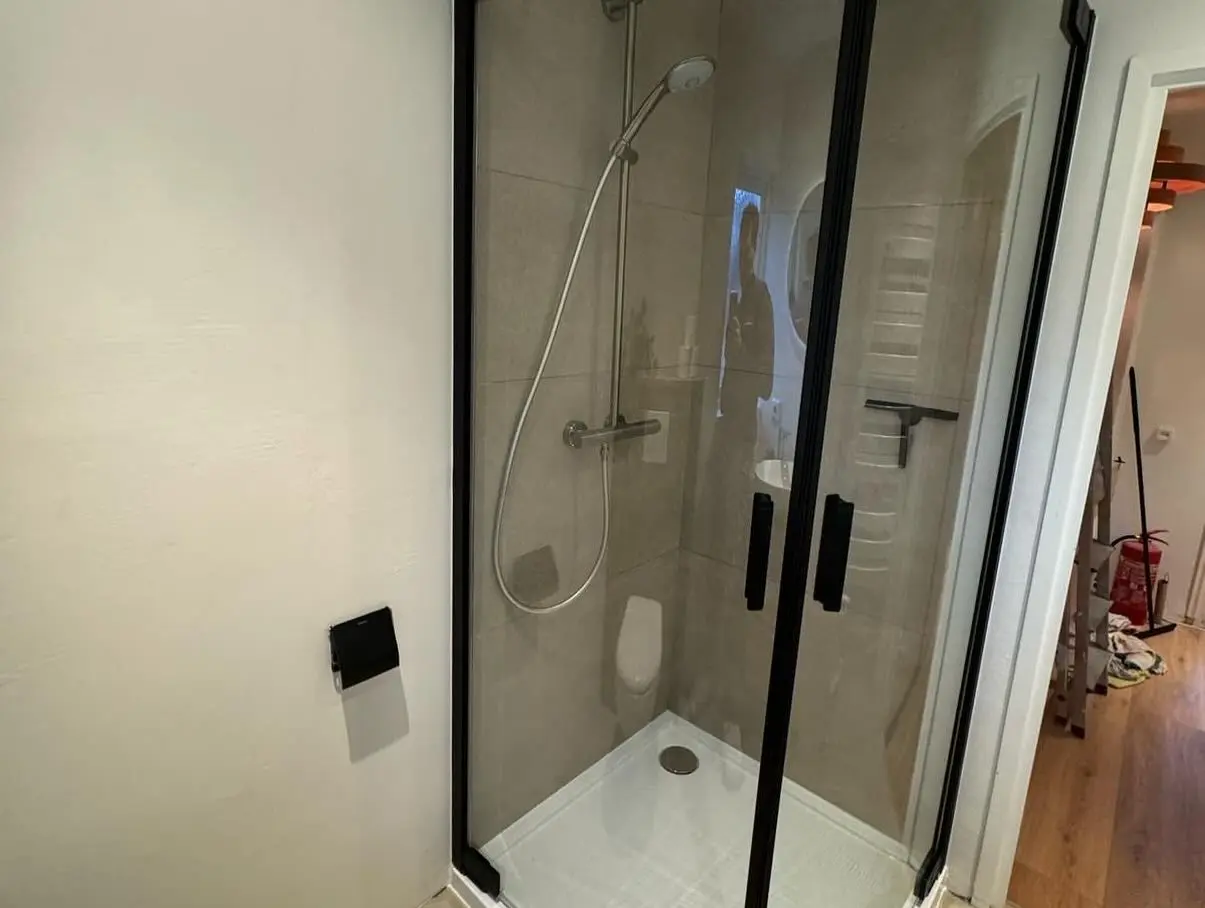 Shower cabin with glass doors and black frame, featuring a sleek showerhead.